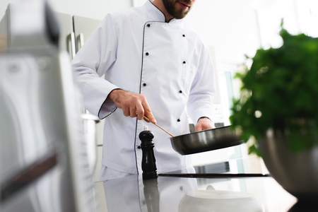 cropped image of chef frying food on frying pan at restaurant kitchenの写真素材