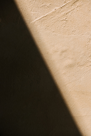 full frame image of rustic beige wall with shadow backgroundの写真素材