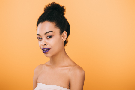 smiling young woman with purple lips isolated on yellowの写真素材
