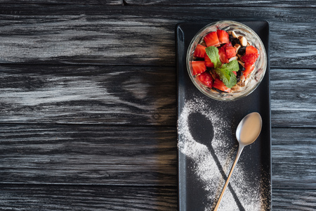 top view of tasty healthy dessert with fruits and spoon on wooden tableの写真素材