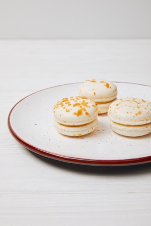 three macarons in plate on white wooden tableの写真素材