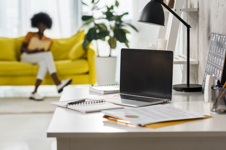 selective focus of laptop on table and african american freelancer at home officeの写真素材