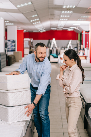 couple with folding mattresses in furniture store with arranged mattressesの写真素材