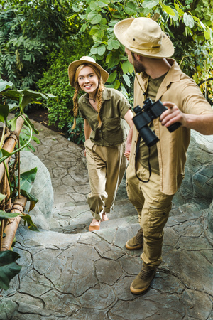 beautiful young couple in safari suits hiking together in rainforestの写真素材