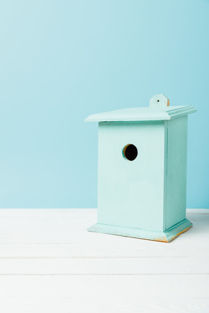close up view of blue birdhouse on wooden surface isolated on blueの写真素材