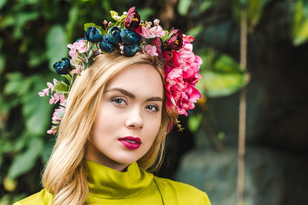 close-up portrait of beautiful young woman with floral wreath looking at cameraの写真素材