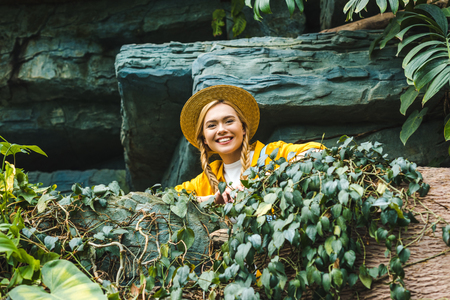 bottom view of happy young woman in straw hat looking at camera in jungleの写真素材