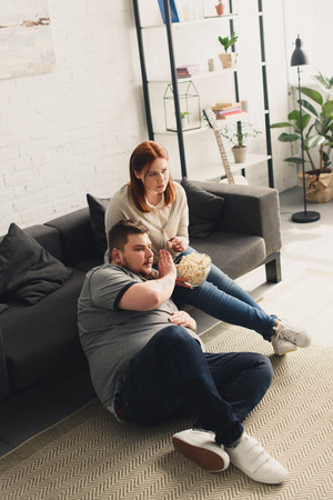 boyfriend and girlfriend watching tv and eating popcorn at homeの写真素材