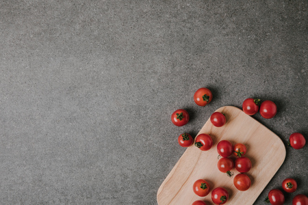 top view of fresh ripe tomatoes on wooden board on greyの写真素材