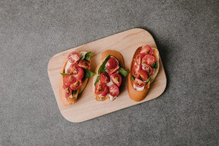 top view of gourmet italian bruschetta on wooden board on greyの写真素材