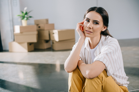 beautiful young woman looking at camera while sitting in new office during relocationの写真素材