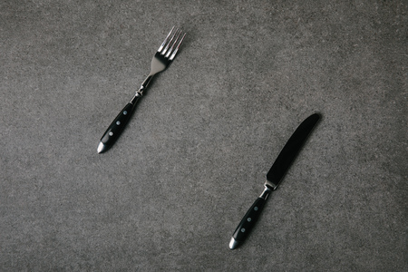 top view of fork and knife on grey background