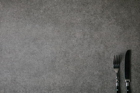 top view of shiny fork and knife on grey background