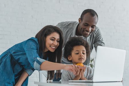 african american mother pointing on something at laptop at home