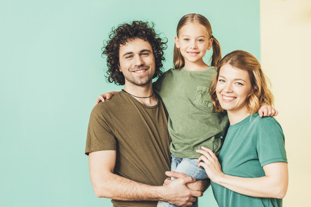 happy parents carrying adorable little daughter and smiling at cameraの写真素材