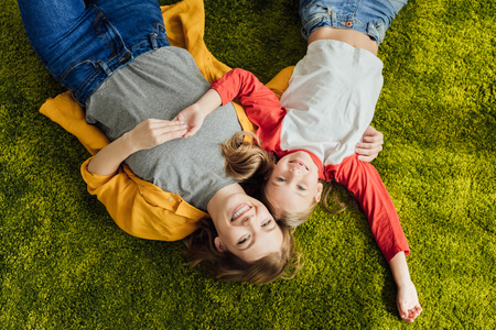 top view of happy mother and daughter lying together and smiling at cameraの写真素材