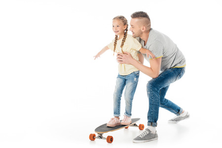 father helping little daughter skating on skateboard isolated on whiteの写真素材