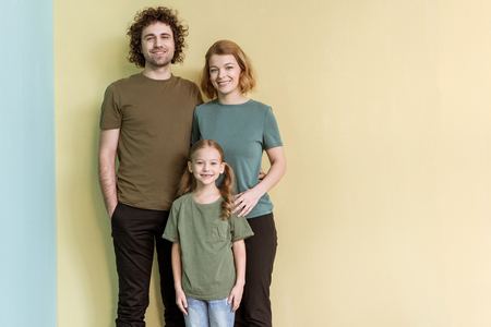 happy family with one child standing together and smiling at cameraの写真素材