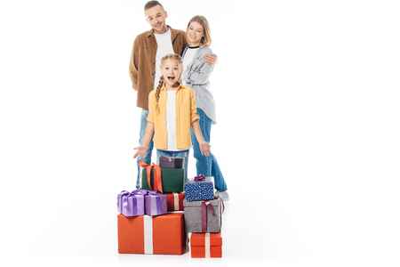excited kid with pile of wrapped gifts and parents behind isolated on whiteの写真素材
