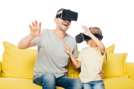 father and daughter in virtual reality headsets on yellow sofa isolated on whiteの写真素材
