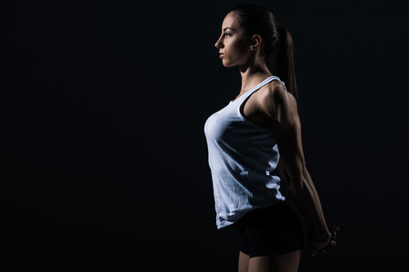 beautiful athletic sportswoman stretching arms, isolated on blackの写真素材
