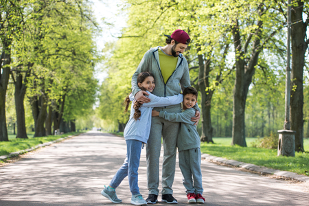 happy little children embracing father in parkの写真素材