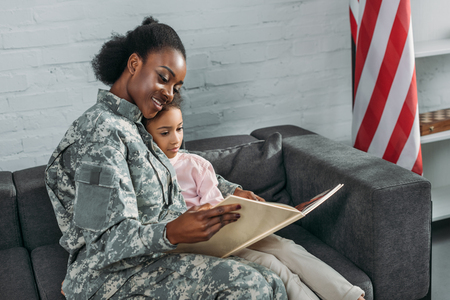 Mother soldier and african american child reading bookの写真素材