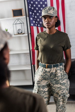 Attractive african american woman in camouflage clothes posing by the mirrorの写真素材