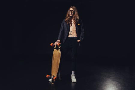 fashionable handsome man posing with skateboard, on blackの写真素材