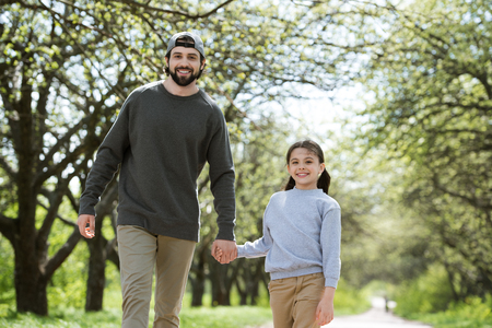father and daughter walking and holding hands in parkの写真素材