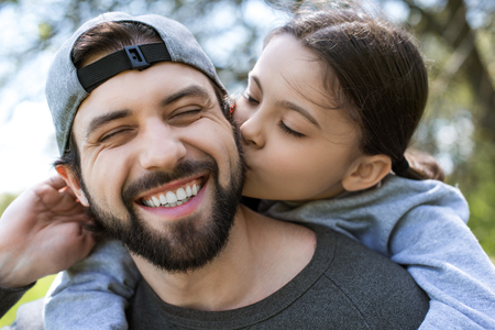 daughter kissing cheek of smiling fatherの写真素材
