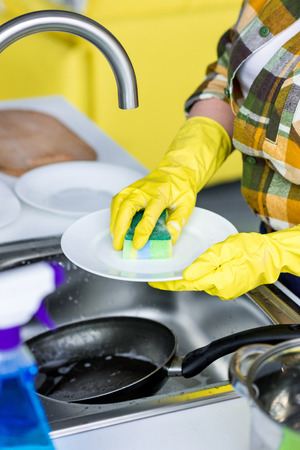 cropped image of woman washing plate with washing sponge in kitchenの写真素材