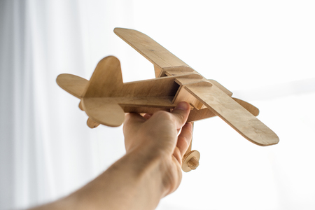 cropped shot of man holding wooden toy plane in handの写真素材