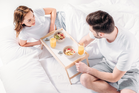 high angle view of young couple having breakfast in bed in morning togetherの写真素材