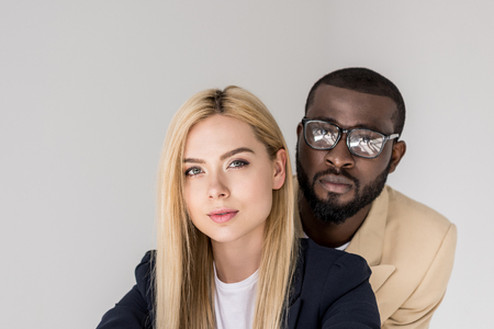 portrait of beautiful young multiethnic couple looking at camera isolated on greyの写真素材