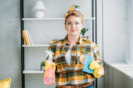 beautiful woman showing spray bottle and rag for cleaning at homeの写真素材