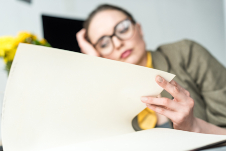 close-up view of bored businesswoman reading book at workplaceの写真素材