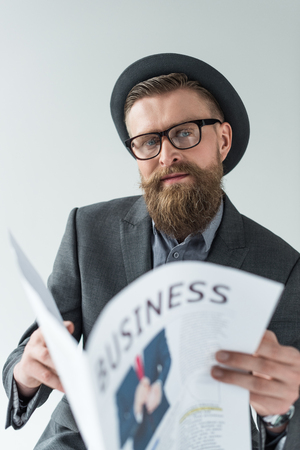Businessman with vintage mustache and beard reading business newspaper isolated on light backgroundの写真素材