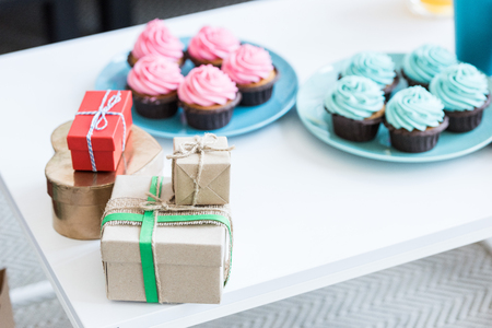 pink and blue cupcakes and gift boxes on white table, baby-party conceptの写真素材