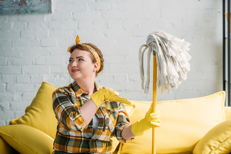 beautiful woman pointing on mop at homeの写真素材
