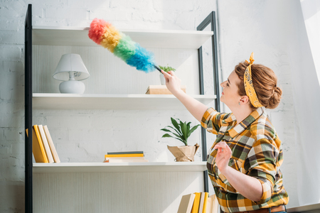 beautiful woman dusting shelves at homeの写真素材