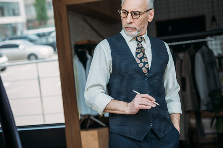 senior tailor holding pencil at sewing workshop and looking down