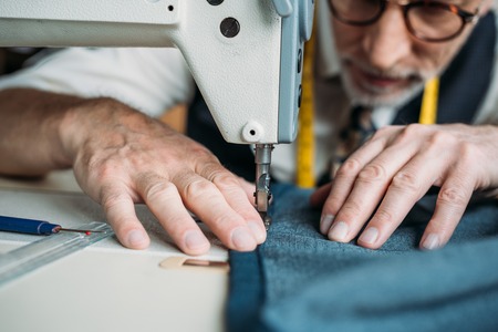 cropped image of dressmaker sewing cloth with sewing machine at sewing workshopの写真素材