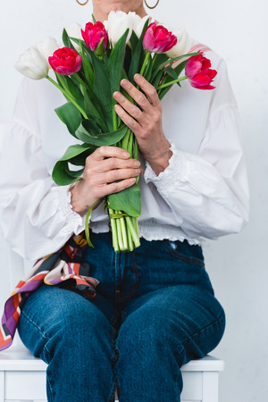cropped view of woman with bouquet of tulip flowers, isolated on whiteの写真素材