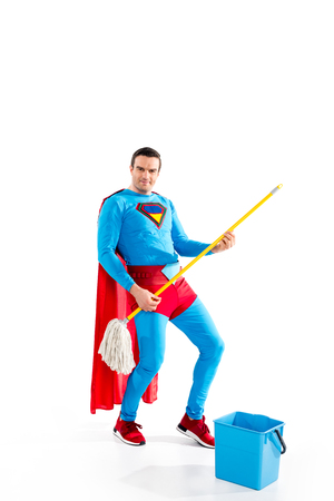 handsome superhero having fun with mop and smiling at camera on whiteの写真素材