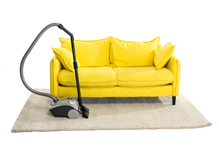 bright yellow sofa and vacuum cleaner on carpet isolated on whiteの写真素材