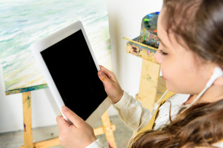 kid listening to music with tablet in workshop of art schoolの写真素材