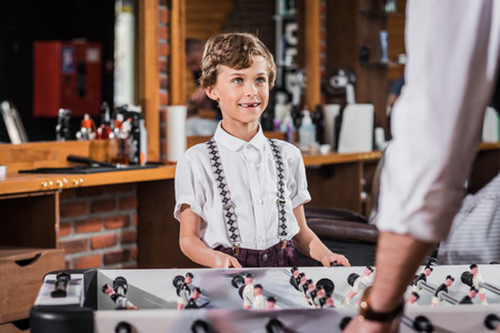 happy little kid playing table football with father