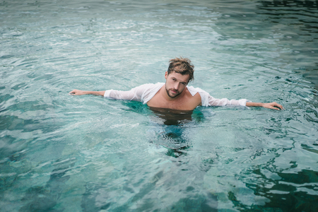 sexy handsome man in swimming pool in Bali, Indonesiaの写真素材
