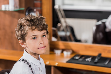 curly little kid looking at camera at barbershopの写真素材